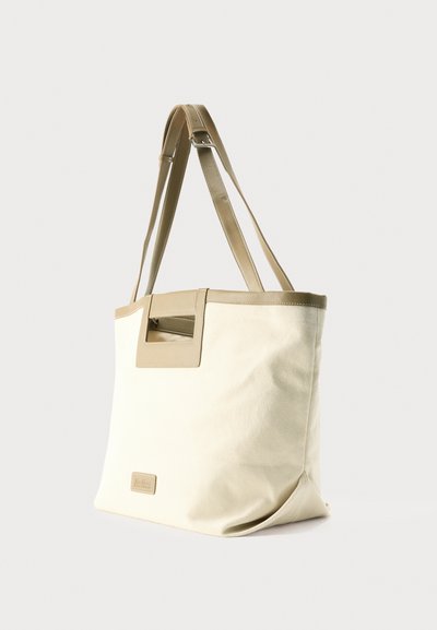 Τσάντα ώμου από καμβά σε κρεμ χρώμα με μπεζ δερμάτινες λεπτομέρειες, ρυθμιζόμενους ιμάντες ώμου και ορθογώνια λαβή με περικοπή.