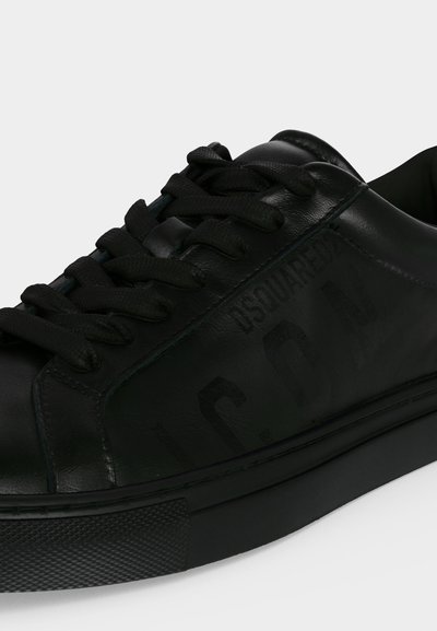 Baskets en cuir noir avec des lacets noirs et une semelle en caoutchouc texturée, avec un marquage en relief subtil sur le panneau latéral.
