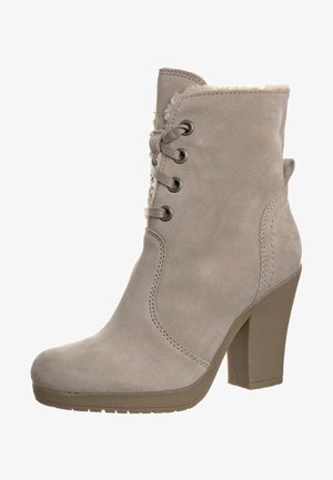 Bottine en daim beige avec talon épais, lacets sur le devant et doublure duveteuse visible sur le bord supérieur.