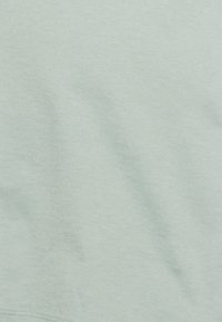 Tecido de algodão verde-claro com uma textura suave, apresentando rugas subtis e um design simples. Sem padrões ou acentos visíveis.