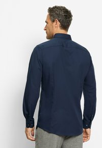 Marineblaues Langarmhemd mit strukturiertem Kragen, knöpfbaren Manschetten und glatter Textur. Verfügt über ein tailliertes Rückendesign.