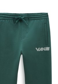 Pantalones de chándal verdes con cintura elástica, cordón, bolsillos laterales y un logo plateado de "VANS" en el lado derecho. Material suave y texturizado.