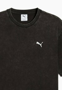 Zwarte katoen T-shirt met een ronde hals, korte mouwen en een klein wit Puma-logo op de borst, met een vintage wassing textuur.