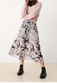 Maglione rosa chiaro in maglia con scollo a V, abbinato a una gonna plissettata alla lunghezza del ginocchio con un motivo marmorizzato in bianco e nero e stivali combat neri.