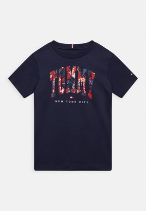 Camiseta de manga corta azul marino con "TOMMY" en rojo y patrón floral, texto "NEW YORK CITY" y pequeño logo de la bandera de Tommy Hilfiger debajo.