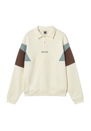 Kremfarget langermet poloskjorte med blå og brune fargeblokker på ermene og teksten "KAOTIKO" midt foran.