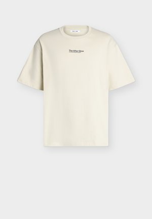 Μπεζ T-shirt με κοντά μανίκια και στρογγυλή λαιμόκοψη, με μικρό μαύρο κείμενο "The After Glow sending energy into space" στο στήθος.