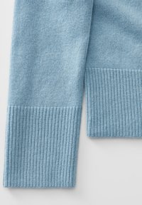 Maglione lavorato a maglia di colore azzurro chiaro con una sottile texture e polsini a costine, che mostra una finitura morbida e liscia.
