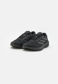Black athletic shoes with a mesh upper, textured surface, three horizontal stripes, flat sole, and lacing system, designed for comfort and support.