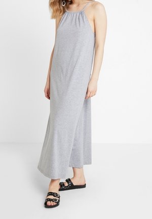 Szara, bezrękawnikowa sukienka maxi z marszczonym dekoltem i zwiewnym materiałem. Do tego czarne sandały typu slide z ozdobnymi akcentami.