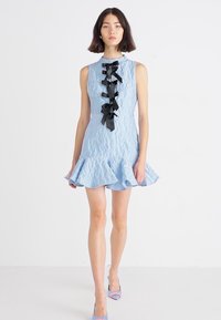 Vestito senza maniche di un azzurro chiaro in tessuto testurizzato, con orlo arricciato e dettagli in nastro nero lungo la parte anteriore.