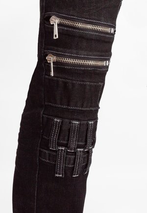 Pantalons en denim noir avec plusieurs poches zippées et un panneau texturé avec des accents cousus sur la cuisse. Détails en matériel argenté.