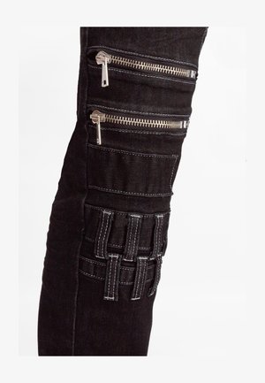 Pantalons en denim noir avec plusieurs poches zippées et un panneau texturé avec des accents cousus sur la cuisse. Détails en matériel argenté.
