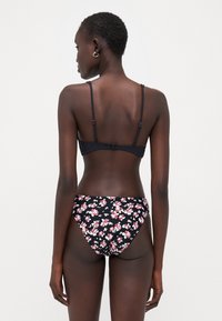 Svart bikinitopp med tynne stropper og krokfeste; bunn med blomstermønster i svart, rosa og hvitt. Jevnt tekstur, tettsittende design.