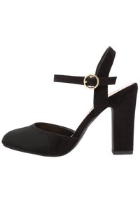 Černá vysoká bota na podpatku vyrobená z semiše, s kulatou špičkou, kotníkovým páskem se zlatým kulatým sponou a silným blokovým podpatkem.