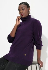 Lila Rollkragenpullover aus leichtem Material mit Dreiviertelärmeln, der am Saum eine goldene Akzentuierung und gerippte Bündchen aufweist.
