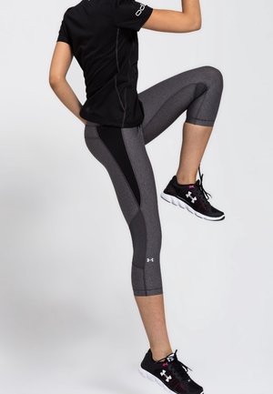 Musta urheilutoppi, harmaat lyhyet leggingsit sivupaneelilla ja mustat urheilukengät valkoisilla yksityiskohdilla. Teksturoitu kangas sopii aktiiviseen käyttöön.