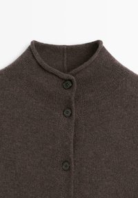 Bruine gebreide cardigan met een hoge kraag, drie zwarte knopen en een gestructureerde afwerking. De stof lijkt zacht en licht pluizig.