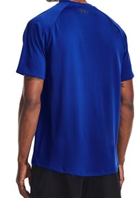 Camiseta atlética azul de manga corta hecha de un tejido suave que absorbe la humedad. Presenta un logo en la parte posterior del cuello y un diseño ajustado.