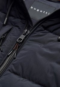 Schwarze Daunenjacke mit Reißverschluss, ausgestattet mit einem strukturierten Außenmaterial und einem Logopatch. Enthält eine verstellbare Kordel und einen robusten Reißverschluss.