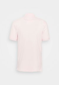 Chemise polo rose clair à manches courtes vue de dos sur fond blanc uni.