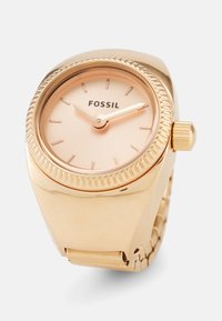 Goldfarbene Fossil-Uhr mit rundem Gehäuse, zart rosa Zifferblatt, dünnen Stundenmarkierungen und einer strukturierten Krone, ausgestattet mit einem flexiblen Armband.