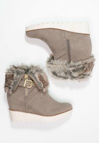 Grå suedestøvler med kilehæle og imiteret pelskant, lynlås i siden og hvid bølget sål. Blød tekstur med guldhardwaredetaljer.