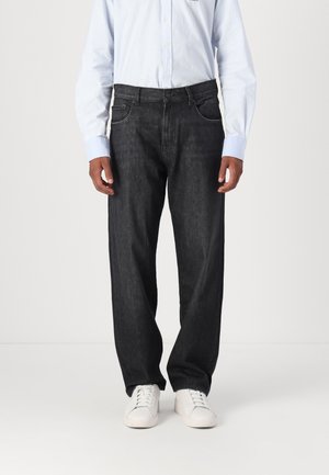 Donkerdenim jeans met een rechte pijp, voorzien van subtiele stikdetails en een klassieke vijf-pocketstijl. Draag ze met een lichtblauw shirt en witte sneakers.
