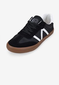 Sneaker nere con tomaia in suede e tessuto, design a righe bianche, lacci neri e suola in gomma. Collo e linguetta imbottiti per il comfort.