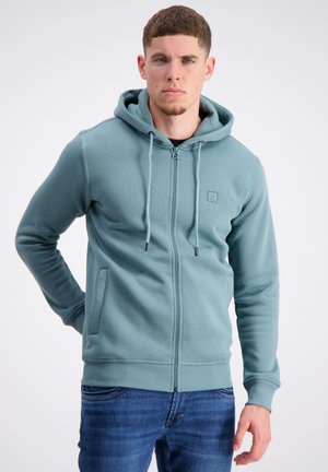 Hooded zip-up sweatshirt in teal, made of soft fabric. Features a small logo, drawstrings, and front pockets. Finished with ribbed cuffs and hem.