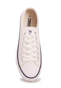 Zapatilla de lona blanca con cordones planos blancos, puntera redonda, suela de goma y ribete azul marino a lo largo de la suela. Talla 39 impresa en el interior.
