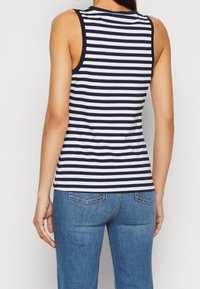 Marinblå och vit randig linne med en figursydd design och rundad nederkant. Har en rund halsringning och breda ärmhål, tillverkad av mjukt material.