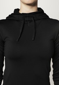 Sudadera negra hecha de una tela suave y elástica. Presenta una capucha con cordón, corte ajustado, mangas largas y detalles de costura sutiles.