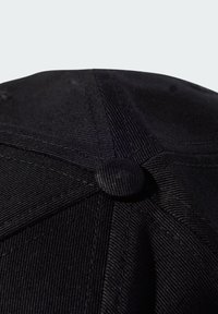 Čierna čiapka s textúrovanou tkaninou, zaobleným tvarom a centrálnym gombíkom na vrchu. Viditeľné stehy a malé detaily zvýrazňujú dizajn.