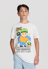 Biała bawełniana koszulka z kolorową grafiką postaci z kreskówki w pomarańczowej koszuli, niebieskich spodniach i zielonymi akcentami.