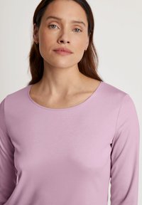 Lichtpaarse langemouwen top met een brede, ronde halslijn en een gladde textuur. Eenvoudig ontwerp, geen zichtbare patronen of accenten.