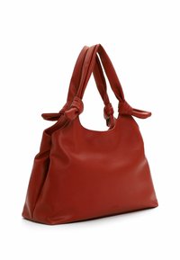 Bolso de mano de cuero rojo con textura suave, asas anudadas y forma redondeada. Presenta un diseño espacioso y un branding mínimo en el lateral.