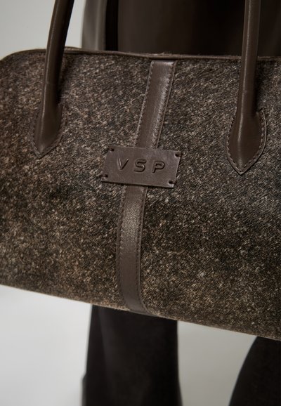 Borsa a mano in feltro marrone con dettagli in pelle, dotata di un'etichetta in pelle impressa con "VSP" e manici robusti e allungati.