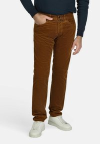 Bruine corduroy broek met een rechte pasvorm, voorzien van vijf zakken, een knoopsluiting en een zachte textuur. Gepaard met witte sneakers.
