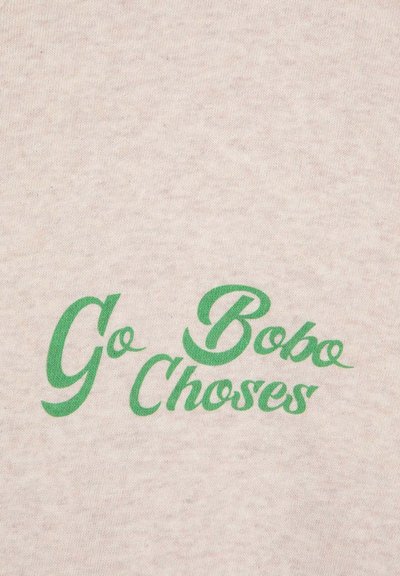 Light beige cotton fabric featuring green cursive text that reads “Go Bobo Choses.” The print is bold with a slightly textured finish.