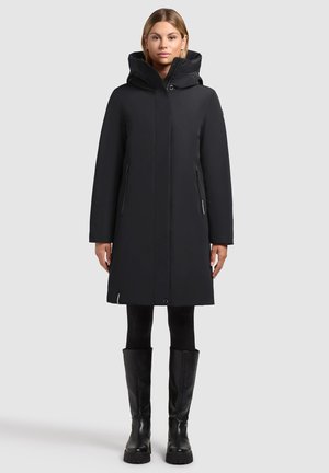 Zwarte waterdichte parka met een hoge kraag, afneembare capuchon en ritssluitingen aan de zijkant. Gladde textuur, knielange ontwerp en minimale accenten.