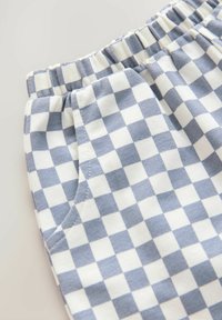 Shorts légers en coton présentant un motif à carreaux bleu et blanc, une taille élastique et des poches latérales. Texture lisse avec des coutures surpiquées.