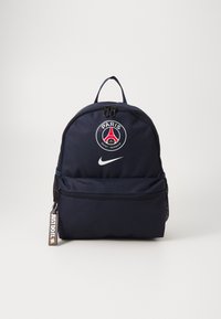 Sac à dos en tissu bleu marine de forme arrondie, comportant un logo Paris Saint-Germain, un logo Nike et une poche zippée à l'avant.