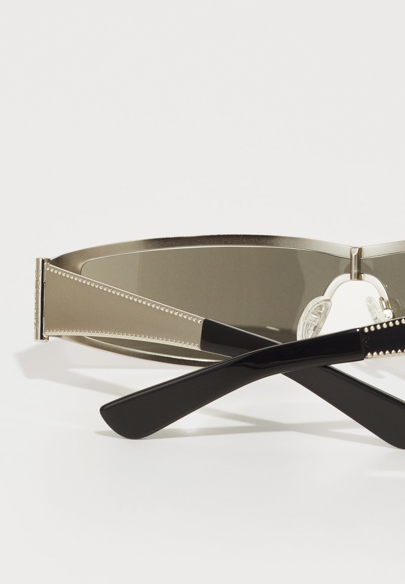 Metallisch graue Sonnenbrille mit einem geschwungenen Rahmen, dunklen, getönten Gläsern und schwarzen Acetat-Bügeln, die mit dekorativen Kanten und einer polierten Oberfläche versehen sind.