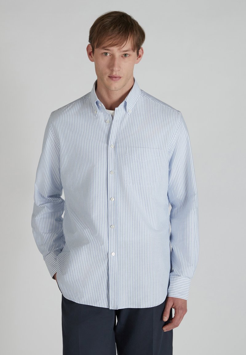 Camicia a maniche lunghe con bottoni in blu chiaro e strisce verticali bianche, con colletto button-down e taschino sul petto. Tessuto morbido.