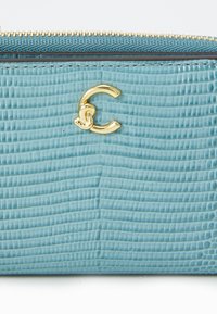 Teal textured faux leather wallet with gold hardware, featuring a prominent letter 'C' logo and a zip closure along the top edge.