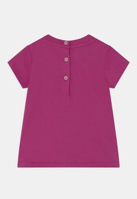 Fialové bavlněné tričko s krátkým rukávem, se kulatým výstřihem a knoflíkovým zapínáním na zádech. Hladká textura a jednoduchý design.