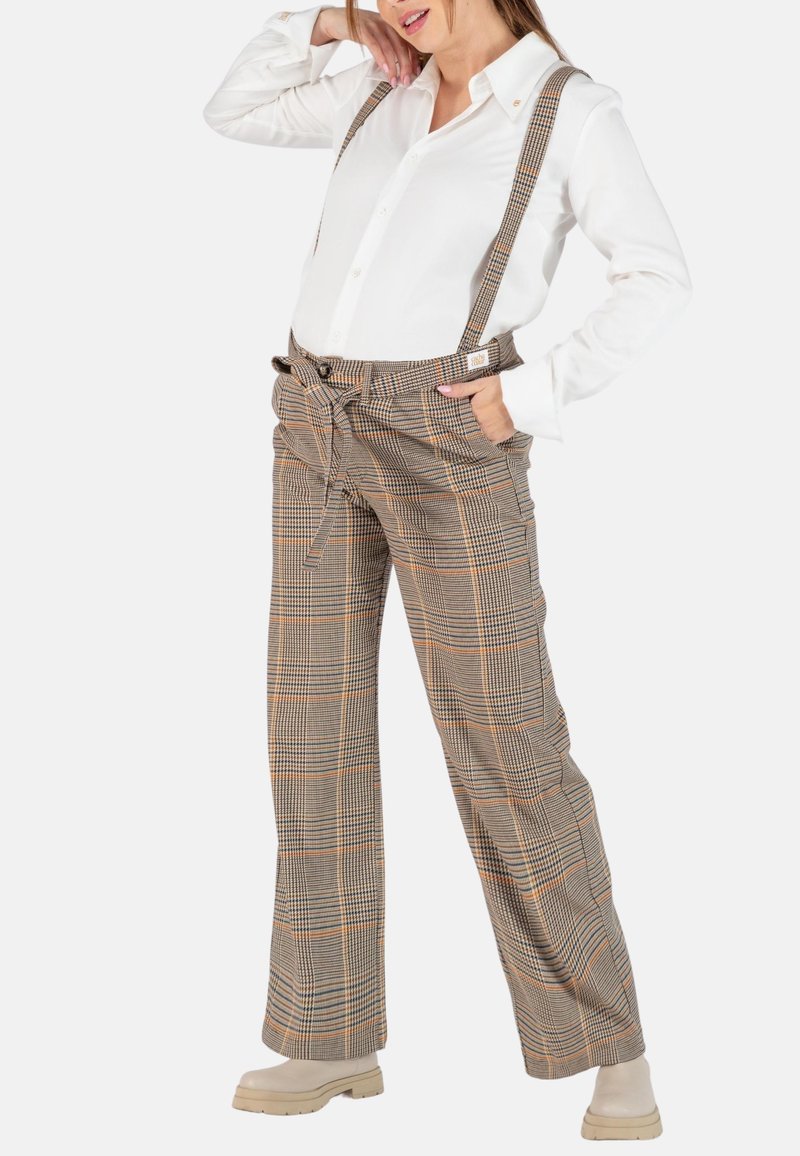 Pantalons à carreaux marron avec bretelles, dotés d'une taille haute, de poches avant et d'une ceinture à nouer. Assortis avec une chemise blanche à manches longues.