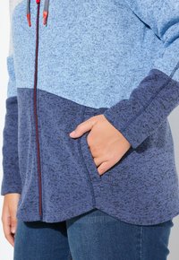 Modrá a námořnická mikina na zip vyrobená z texturované látky, s dvoubarevným designem, plným zipem vpředu a boční kapsou na ruce.