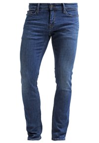 Slim-fit jeans i blå denim med en urtvättad finish, femfickorsdesign och bruna sömmar. Tyget har en mjuk текстur och en lätt stretch.